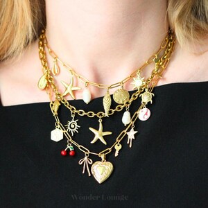 May include: Gold-toned layered necklaces with various charms, including starfish, shells, suns, and a heart-shaped locket. The necklaces are worn against a black top, creating a contrast that highlights the jewelry's details.