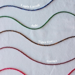 May include: Six strands of gemstone beads, each labeled with its name: Turquoise, Lapis Lazuli, Jade, Tiger Eye, Garnet, and Ruby.