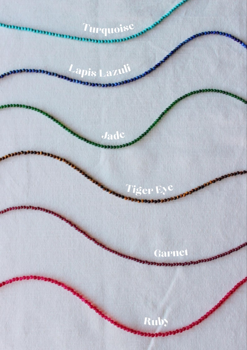May include: Six strands of gemstone beads, each labeled with its name: Turquoise, Lapis Lazuli, Jade, Tiger Eye, Garnet, and Ruby.