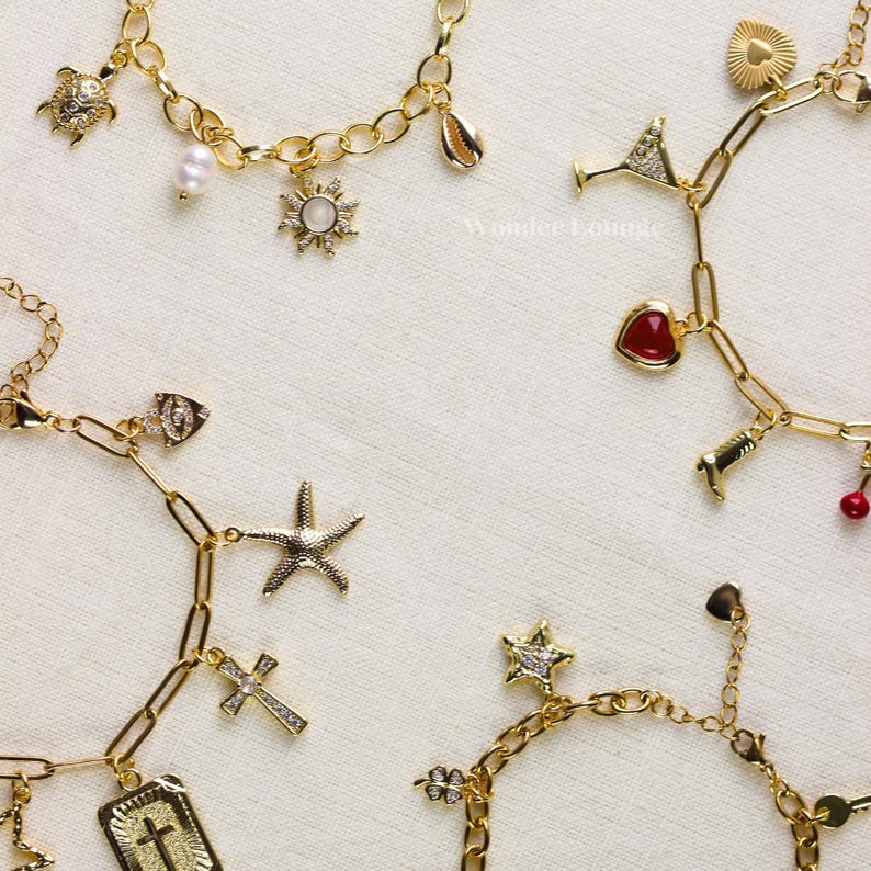 May include: Gold-toned charm bracelets with various pendants, including a turtle, sun, seashell, starfish, cross, and heart. The charms are detailed with crystals and pearls. The bracelets are displayed on a white surface.