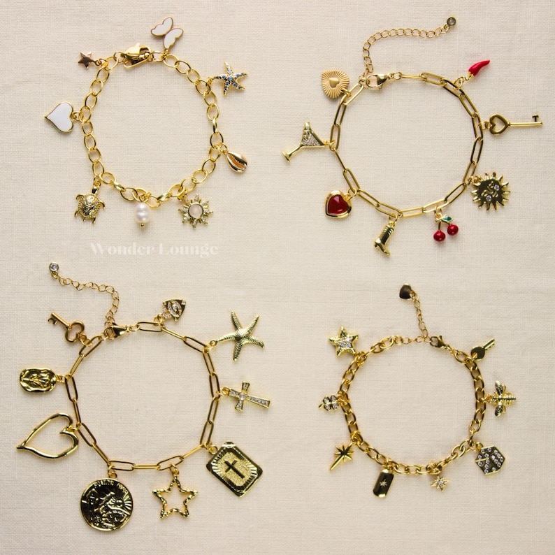 May include: Four gold-colored charm bracelets with various pendants, including stars, hearts, crosses, and a turtle. The bracelets have a chain link design and are displayed on a light-colored surface. The bracelets are from Wonder Lounge.