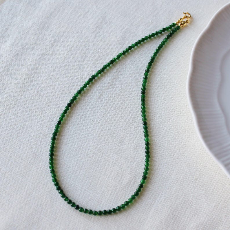 May include: A green jade bead necklace with a gold clasp.