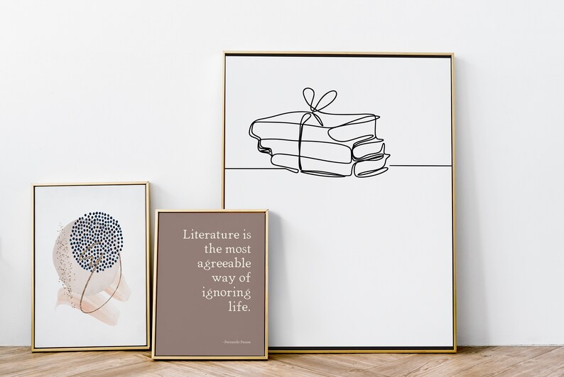 Puede incluir: Tres impresiones enmarcadas con marcos dorados. La impresi&oacute;n de la izquierda presenta un dise&ntilde;o abstracto azul y blanco sobre un fondo de acuarela rosa. La impresi&oacute;n del centro presenta un fondo marr&oacute;n con texto blanco que dice "La literatura es la forma m&aacute;s agradable de ignorar la vida." La impresi&oacute;n de la derecha presenta un dibujo de l&iacute;nea negra de una pila de libros atados con una cinta.