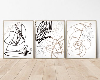 Puede incluir: Conjunto de tres impresiones de arte abstracto con líneas negras y doradas sobre un fondo blanco. Las impresiones están enmarcadas en oro.