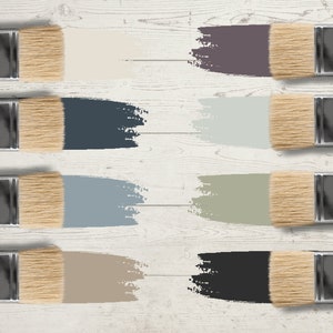 May include: Eight paintbrushes with natural bristles and wooden handles, each displaying a different color swatch. The colors include shades of beige, blue, gray, and black, arranged on a white wooden surface.