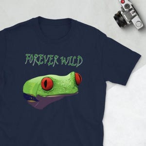May include: Navy blue t-shirt with a green frog graphic and the text "FOREVER WILD" in green. The frog has red eyes and a textured appearance. The shirt is a casual wear item, suitable for everyday wear.
