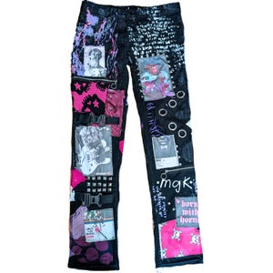 Op de afbeelding: Zwarte denim jeans met patchwork en versieringen. Kenmerken zijn roze en paarse accenten, metalen studs, ritsen en diverse grafische patches. De jeans hebben een uniek, artistiek ontwerp.