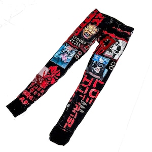 Flat laid skinny custom made black pair with prints containing various horror movies, red and black patchwork, abstract painting, studs, red laces hanging down, chain and eyelets.