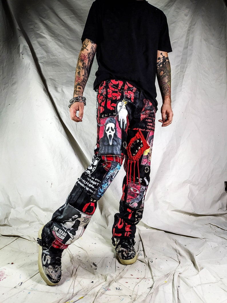Model showing a custom made black pair with prints containing various horror movies, red and black patchwork, abstract painting, studs, red laces hanging down, chain and eyelets.