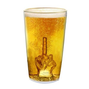 Könnte beinhalten: Ein hohes Glas gefüllt mit goldenem Bier. Eine durchsichtige Glashand, die den Mittelfinger zeigt, ist im Bier versunken.