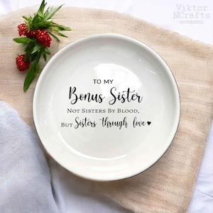 May include: White ceramic dish with a black inscription that reads "To my Bonus Sister Not Sisters by Blood, But Sisters through love".