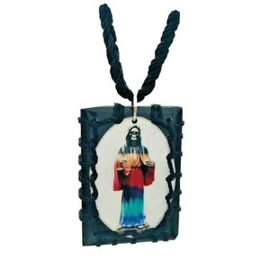 May include: A black cord necklace with a square pendant featuring a colorful image of a skeleton figure. The pendant is framed with black rope.