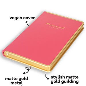 May include: A pink personal planner with the word "MONACO" at the top. The planner has a vegan cover, matte gold metal cover edge protector, and stylish matte gold gilding. The words "Personal Planner" are written in gold script.