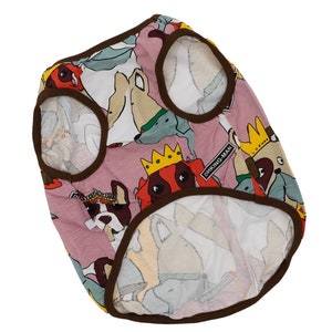 May include: A pink dog vest with a brown trim and a multi-colored print of cartoon dogs. The vest has the text "DHKING-MAN" printed on it.