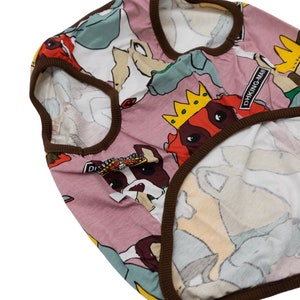 May include: A pink dog shirt with a brown trim. The shirt features a repeating pattern of dogs wearing crowns and the text "DHKING MAN".