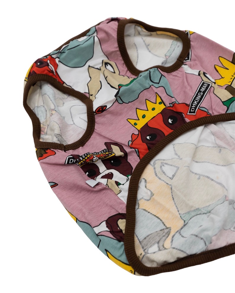 May include: A pink dog shirt with a brown trim. The shirt features a repeating pattern of dogs wearing crowns and the text "DHKING MAN".