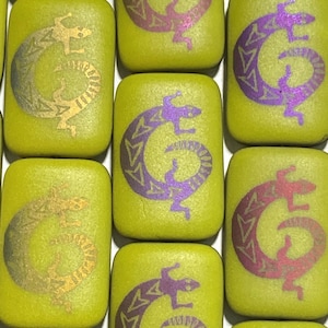 May include: A collection of green ceramic tiles with a repeating pattern of a stylized lizard in various colors, including purple, gold, and red.