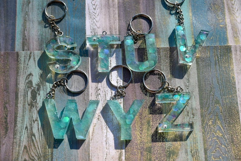 Pu&ograve; includere: Portachiavi con le lettere S, T, U, V, W, Y e Z. Ogni lettera &egrave; realizzata in resina trasparente con una tonalit&agrave; verde acqua e glitter incorporati. I portachiavi hanno anelli e catene in metallo color argento.