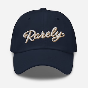 May include: A navy blue baseball cap with the word "Rarely" embroidered in white with a gold outline.