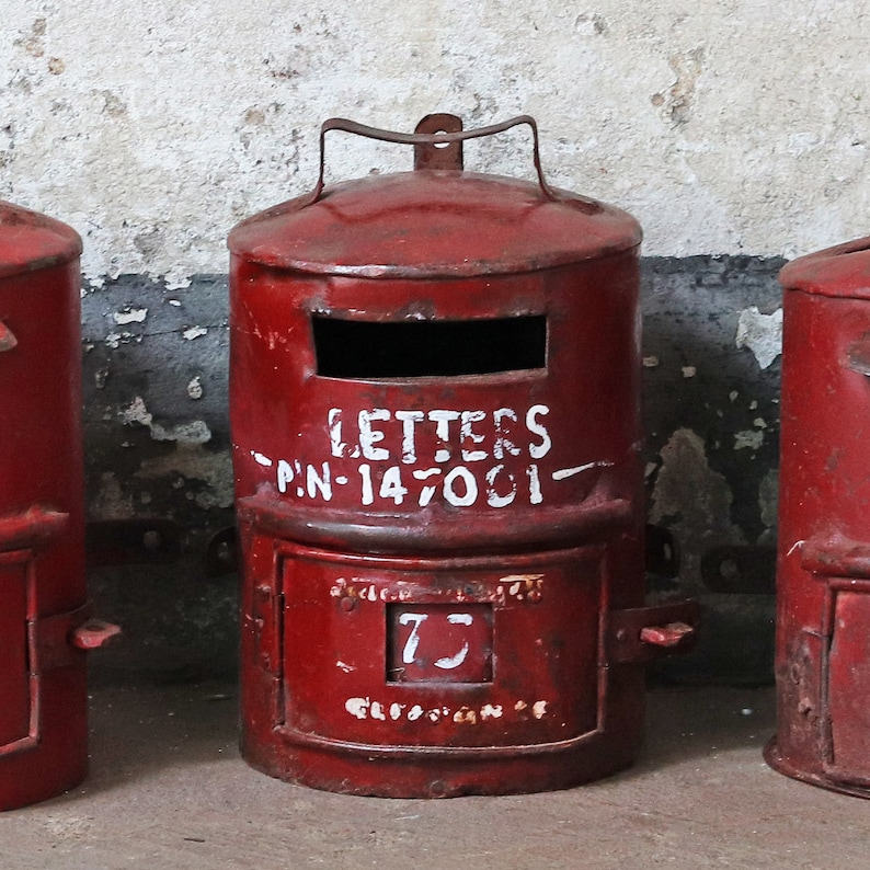 May include: Three red metal mailboxes with a white painted inscription that reads "LETTERS - PIN-147001 -" on the middle mailbox. The mailbox on the right has a number "7" painted on it.