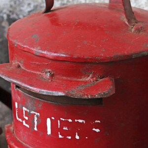 May include: A red metal mailbox with a white inscription that reads "LETTERS". The mailbox has a flap on the top and a handle on the side.