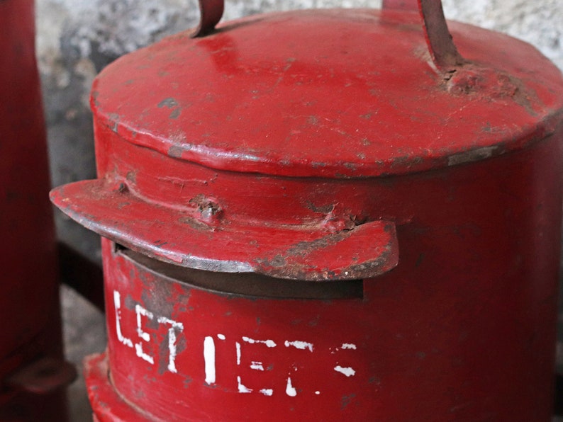 May include: A red metal mailbox with a white inscription that reads "LETTERS". The mailbox has a flap on the top and a handle on the side.