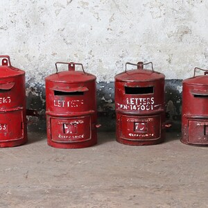 May include: Four red vintage mailboxes with white lettering. The mailboxes have a slot for letters and a small door on the bottom. The mailboxes are labeled "Letters", "Letters", "Letters PN-147001", and "Letters".