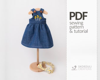 May include: PDF sewing pattern and tutorial for a denim dress with yellow flower embroidery. The dress is displayed on a wooden stand with a yellow floral bow.