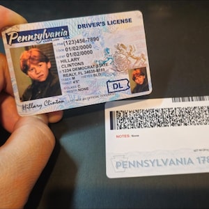 May include: A novelty Pennsylvania driver's license card featuring a portrait of a person with red hair, the name Hillary Clintons, and the text Pennsylvania, Driver's License, 1234 Democrat State, and 1787. The back shows a barcode and Pennsylvania 1787.