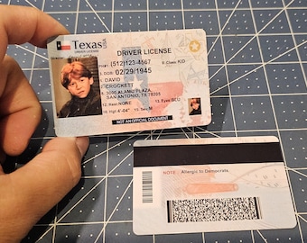 Puede incluir: Una licencia de conducir de Texas con la foto de una persona joven con cabello rojo. La licencia incluye el nombre David Crockett, la fecha de nacimiento y la dirección. La parte posterior tiene una banda magnética y el texto "NOTE: Allergic to Democrats."