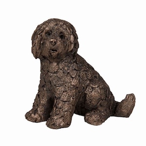 May include: A bronze sculpture of a small, fluffy dog sitting with its head tilted slightly to the side. The dog's fur is sculpted in a textured, layered style, giving it a unique and realistic appearance.
