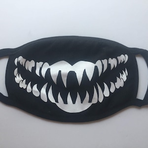May include: Black face mask with a white graphic of a large, toothy grin.