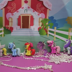 May include: A set of nine colourful My Little Pony necklaces with silver chains. Each necklace features a different pony character with a unique design and colour scheme.
