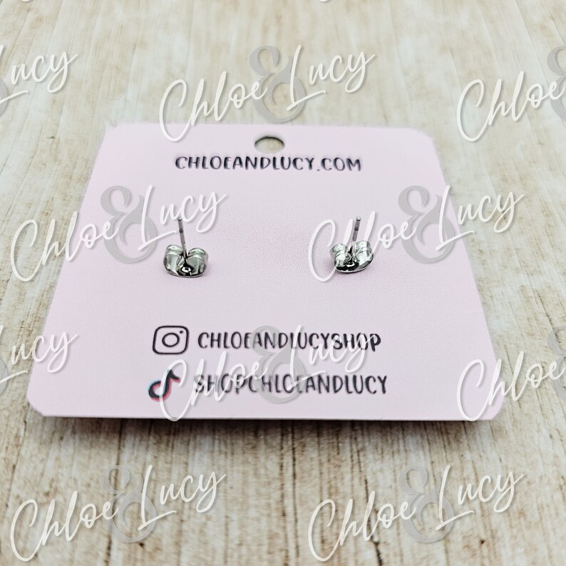 May include: A pair of silver stud earrings on a pink card with the text "Chloe & Lucy" and "CHLOEANDLUCY.COM".