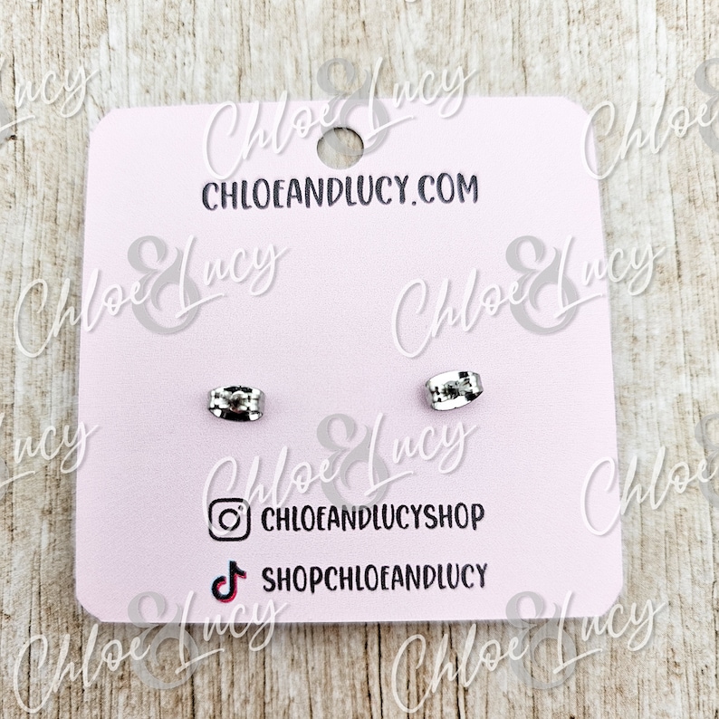 May include: A pair of silver earring backs on a pink card with the text "Chloe & Lucy" and "chloeandlucy.com". The card also includes social media icons for Instagram and TikTok.