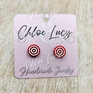 May include: A pair of red and white target-shaped stud earrings on a pink card with the text "Chloe & Lucy Handmade Jewelry".