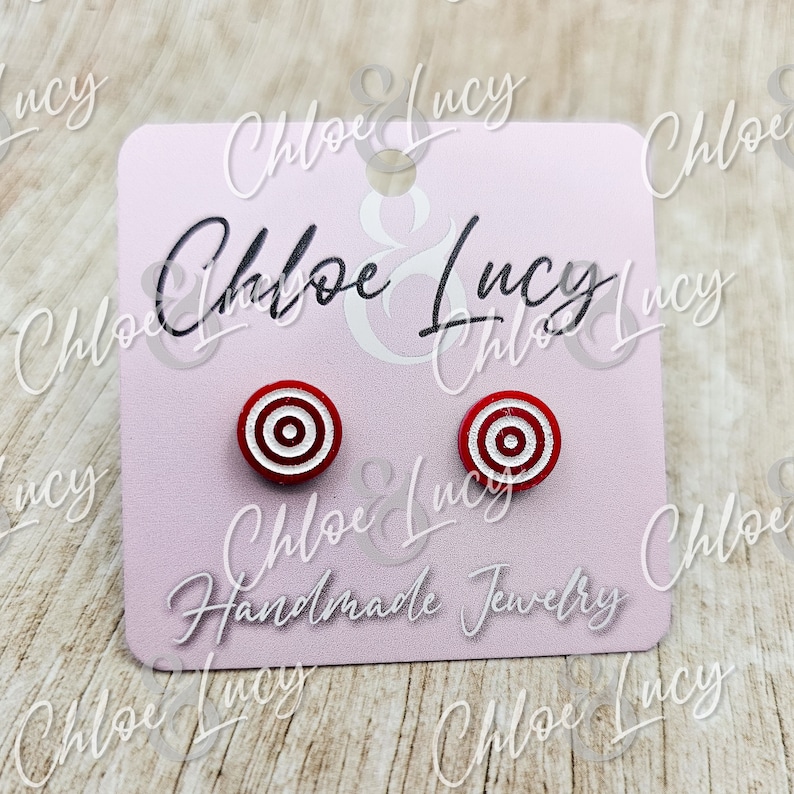 May include: A pair of red and white target-shaped stud earrings on a pink card with the text "Chloe & Lucy Handmade Jewelry".