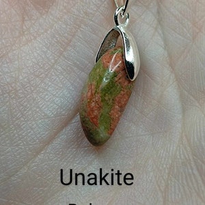 May include: A silver chain necklace with a green and red unakite stone pendant. The pendant is set in a silver bezel and has a smooth, polished finish. The stone is said to promote balance, compassion, and insight.