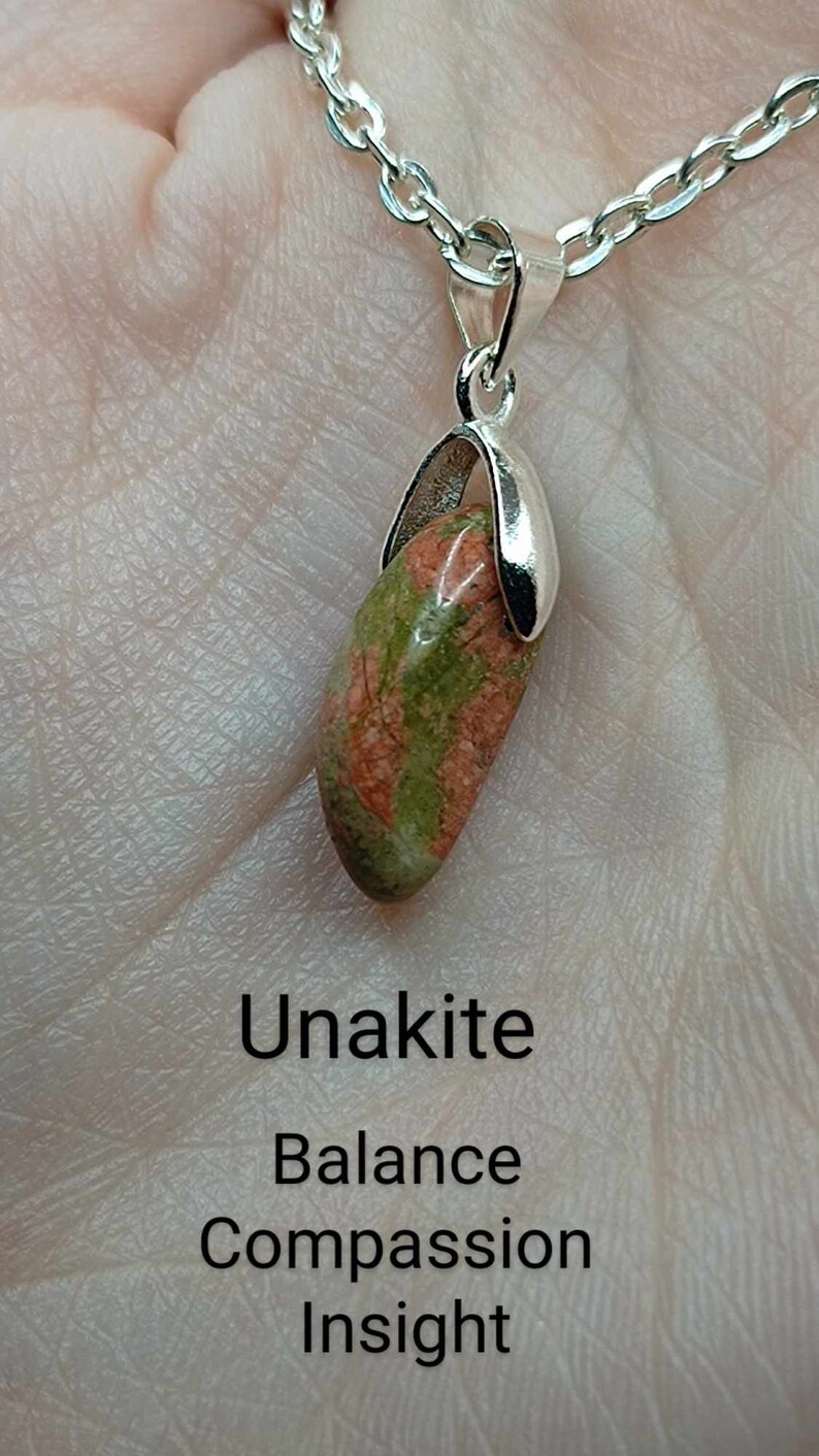 May include: A silver chain necklace with a green and red unakite stone pendant. The pendant is set in a silver bezel and has a smooth, polished finish. The stone is said to promote balance, compassion, and insight.