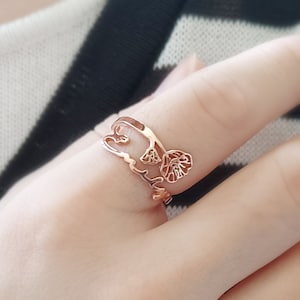 May include: A rose gold ring with a delicate leaf design. The ring is worn on a finger.