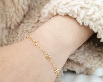 May include: A gold chain bracelet with the word "LOVE" spelled out in small, cursive letters.