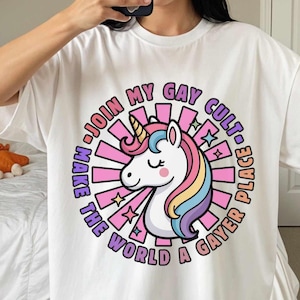 May include: White t-shirt with a colorful unicorn graphic and the text "Join My Gay Cult, Make The World A Gayer Place." The unicorn has a rainbow mane and a gold horn. The shirt is oversized.