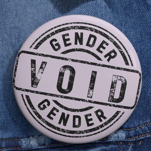 May include: A white ceramic mug with a black handle and the text "But First, Coffee" in a bold, black font. The mug is set against a blurred background, suggesting a cozy setting.