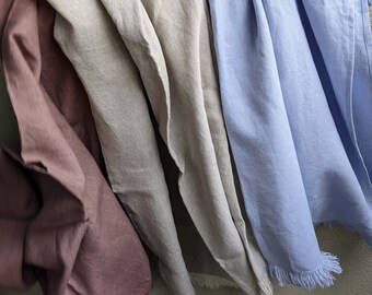 May include: Four linen tea towels hanging on a wall. The towels are in shades of brown, beige, light gray, and light blue.