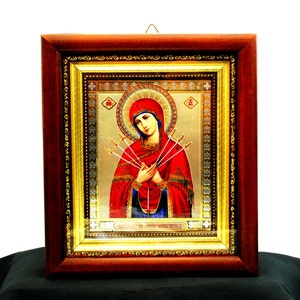 Puede incluir: Un icono religioso enmarcado que representa a la Virgen María con siete espadas que le atraviesan el corazón. El icono está sobre un fondo dorado con detalles intrincados. El marco es de madera oscura con detalles dorados.