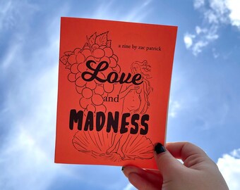 Puede incluir: Un zine rojo con una ilustración negra de una mujer y uvas. El título es "Love and Madness" con el texto "a zine by zac patrick" en la parte superior.