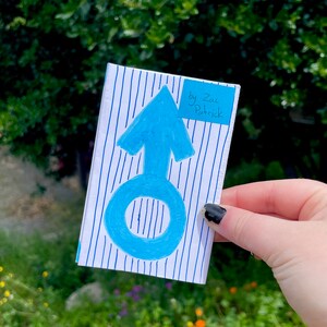 K&ouml;nnte beinhalten: Eine blau-wei&szlig; gestreifte Karte mit einem blauen Pfeil und einem Kreis darauf. Die Karte hat einen blauen Haftnotiz mit dem Text "by Zac Patrick" darauf.