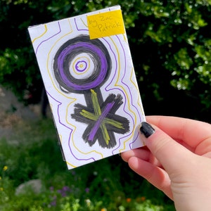 K&ouml;nnte beinhalten: Eine wei&szlig;e Karte mit einem schwarzen und violetten Symbol darauf. Das Symbol ist ein Kreis mit einem kleineren Kreis im Inneren und einer Linie, die sich nach unten erstreckt. Die Karte hat gelbe und violette Linien darauf gezeichnet. Ein gelber Haftnotiz mit dem Text "by Zac Patrick" befindet sich auf der oberen rechten Ecke der Karte.