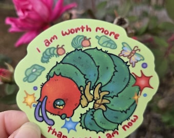 May include: A green sticker featuring a cartoon caterpillar with a red head and yellow feet. The sticker has the text "I am worth more than what I am now" in a circular design with illustrations of leaves, butterflies, and stars.