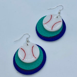 May include: A pair of earrings featuring a white baseball with red stitching on a layered circle of blue, teal, and green felt.